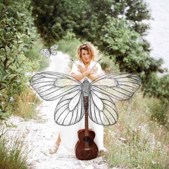 Billede af Stine Michel i naturen med en stor sommerfugl og en guitar. Fotograf: Signe Find Larsen.