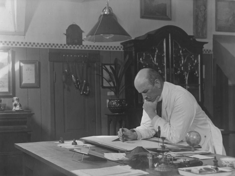 Billede fra Nyborg Lokalhistoriske Arkiv. August Colding står og arbejder ved sit tegnebord. Ukendt fotograf.